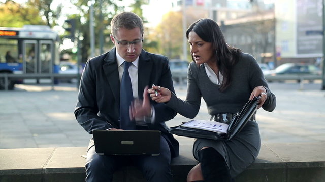 Angry business couple with laptop and documents in the city, ste