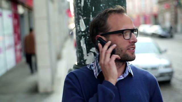 Young man standing on the street and talking on cellphone, stead
