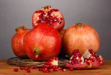 Ripe pomegranates on wicker cradle on grey background
