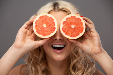 Smiling woman holding two grapefruits in hands