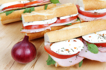 three fresh sandwiches with tomato , ham and mozzarella