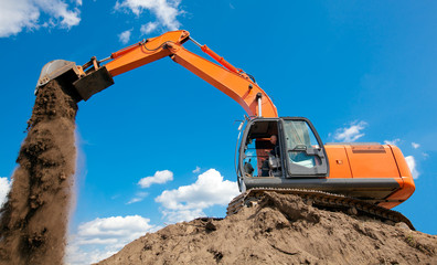 Excavator with metal tracks unloading soil at construction site © Fotolia RAW