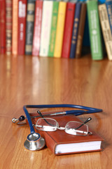 An image of a notebook, spectacles, stethoscope on the desk