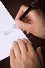 Human hand with pen signing a document
