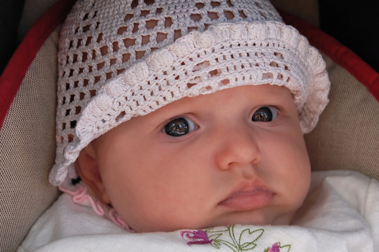 Close-up portrait of a beautiful baby girl in a white knitted ca