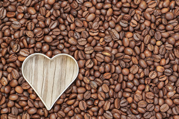 Heart shape in raw coffee beans. On a wooden texture.