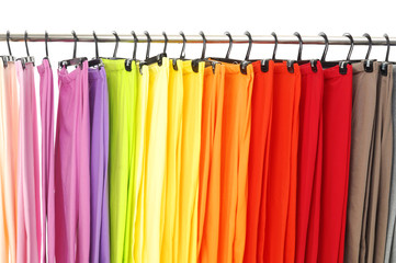 A row of colorful female trousers on hangers