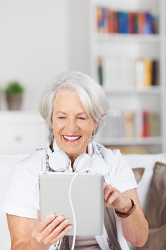 moderne seniorin mit tablet und kopfhörer