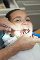 Cute smiling girl having her teeth checked by doctor