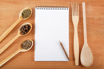 notebook for recipes and spices on wooden table