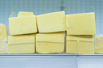 Square cheese pieces on shelves in supermarket