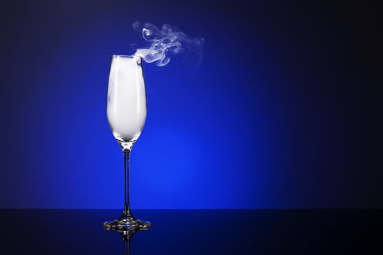 qualmendes sekt glas auf einem spiegel mit blauem hintergrund
