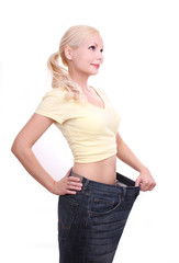 young woman in old jeans after losing weight isolated on white
