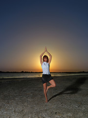 Fototapeta na wymiar young businesswoman meditating yoga position at sunset