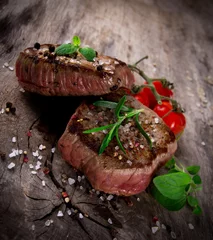 Photo sur Plexiglas Steakhouse Grilled bbq steaks with fresh herbs and tomatoes