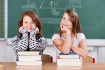 zwei schülerinnen mit büchern im klassenzimmer