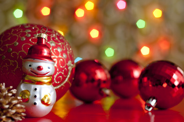 Snow man and baubles against blurred colorful background