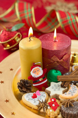 Detail of Christmas cookies with candles on golden plate.