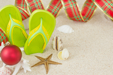 Fototapeta na wymiar Flip Flops in the sand with shells and Christmas decoration.