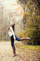 Beautiful girl with umbrella at autumn park.