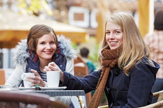 two young women sitting in a sidewalk café