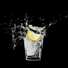 splash in a glass with lemon and ice on a black background