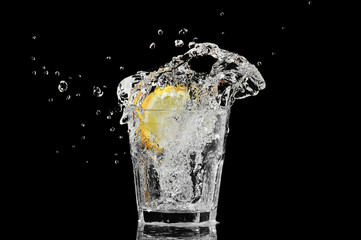 splash in a glass with lemon and ice on a black background