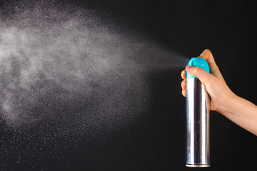 Sprayed air freshener in hand on grey background
