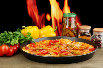 Tasty pepperoni pizza in pan with vegetables on flame
