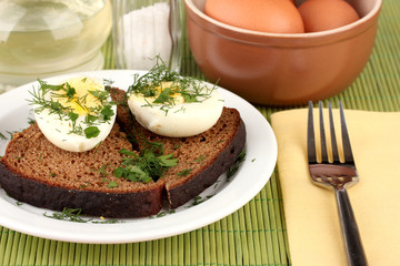 Boiled eggs  on dark bread on green background