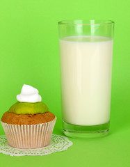 Glass of fresh new milk with cake on green background
