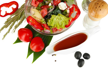 Fresh greek salad in glass bowl surrounded by ingredients for