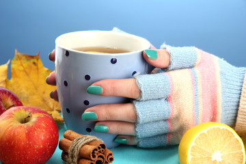 hands holding cup of hot drink and autumn leaves,