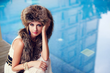 Fashion portrait of a woman in fur next to the swimming pool.