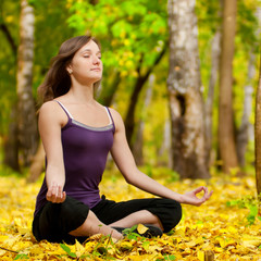 Woman doing yoga exercises in the autumn park