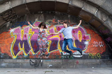 Couple jumping off the ledge with graffiti background