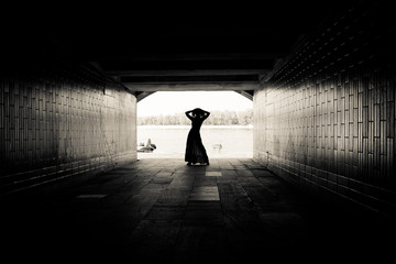 Silhouette of a girl on bright background in a tunnel