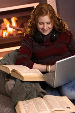 Happy teenage girl learning at home with books