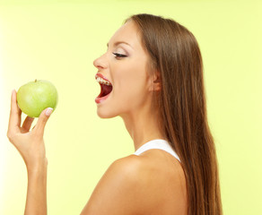 beautiful young woman with green apple, on green background