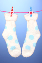 Pair of socks with polka dots hanging to dry over blue