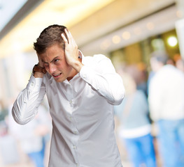 Portrait Of Young Man Covering His Ears With Hand