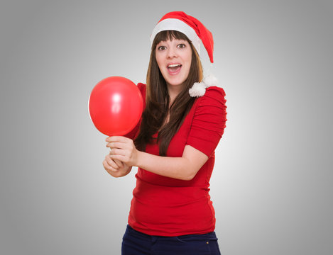 Surprised woman wearing a christmas hat and holding a balloon
