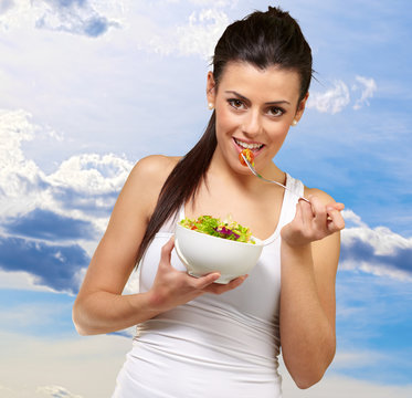 Young woman holding and eating salad
