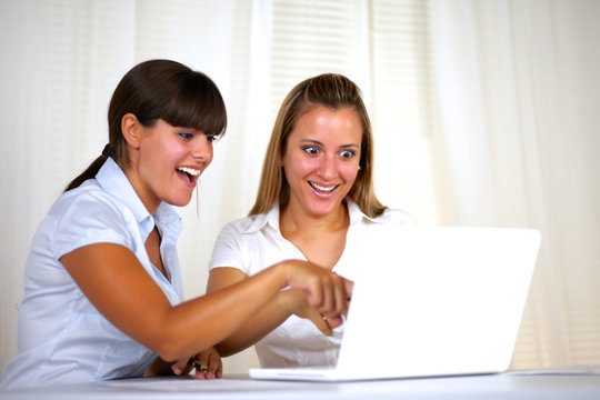 Surprised adult businesswomen reading on laptop