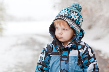 Adorable toddler boy having fun with snow on winter day