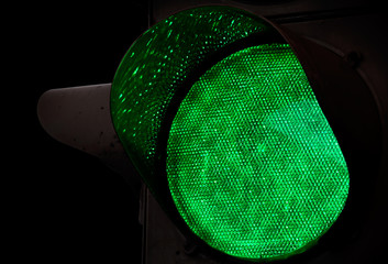 Green traffic light closeup photo above black background