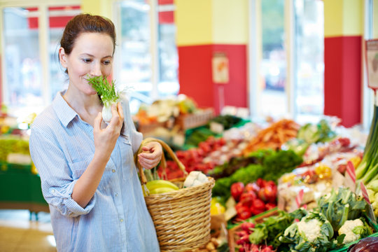 Frau riecht an Fenchel im Supermarkt