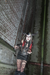 Naklejka premium Scary female demon in front of old dirty brick wall.