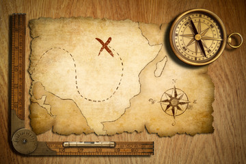 aged treasure map, ruler and old brass compass on wooden table t