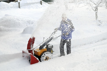 Man is making a path by removing snow with snow blower